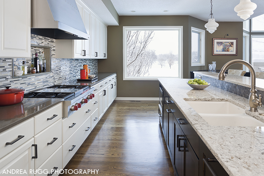 View of high end kitchen showing white cabinets and dark wood island